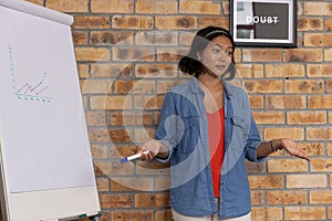 Asian female presenting while holding blue-tipped marker by flipchart with DOUBT print in workshop