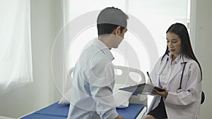 Asian female psychiatrist counseling a male patient and writing symptoms in a notebook