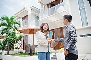 Asian female real estate agent shakes hands with prospective buyers