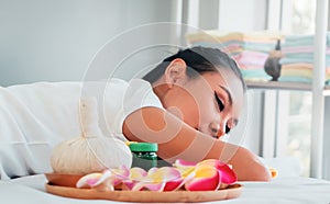 Asian female relaxing in Thai Spa with flower and hot compressed anc candle photo