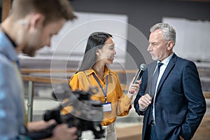 Asian female reporter holding a microphone in her hand