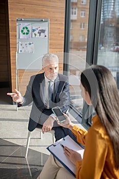 Asian female reporter with long hair having a talk with a mature businessman