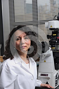 Asian female scientist sitting at microscope