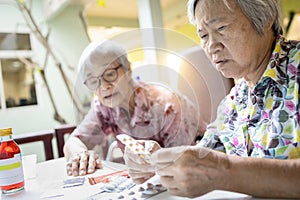 Asian female senior hold medicine pill,elderly woman consult her old people friend,help and read medicine labels drug prescription