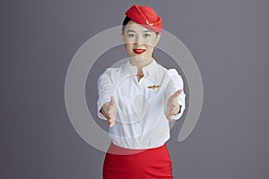 asian female stewardess showing where exits are against gray