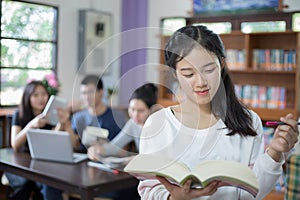 Asian female students holding for selection Book in library