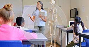 Asian female teacher explaining about skeleton model in classroom 4k