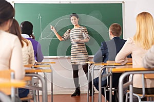 Asian female teacher lecturing to adult students in auditorium
