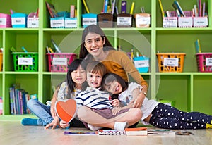 Asian female teacher teaching hug mixed race group of kids in classroom,Kindergarten pre school concept