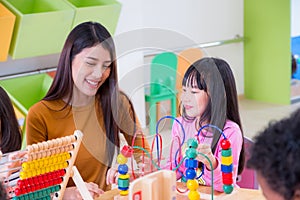 Asian female teacher teaching mixed race kids play toy in classr