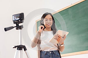 Asian Female teacher using digital tablet giving online lesson on digital camera