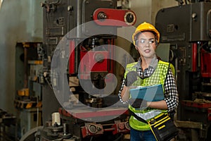 Asian female technician engineer holding clipboard while checking  machines in the factory on business day