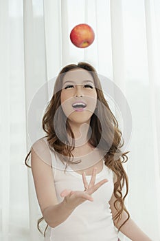 Asian female tossing an red apple