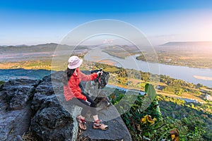 Asian female tourist sits and admires the view at Pha Tak Suea, Thai-Lao border