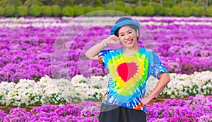 Asian female tourist is smiling cheerfully and looking at camera while posing in blooming pink and white bougainvillea field