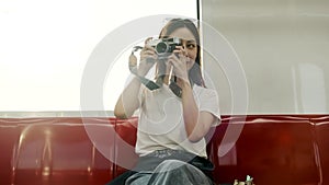 Asian female tourist traveling by train, taking snapshot photos by film camera.