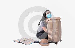 Asian female tourist wearing a mask hugging her suitcase with map, passport.