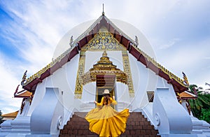 Asian female tourist wearing a yellow dress visits Phumin Temple in Nan province, Thailand