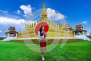 Asian female tourists in Lao costumes visit Pha That Luang in Vientiane, Laos