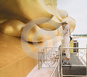 Asian female tourists paying respect at the finger of Giant Golden Buddha at Wat Muang, Ang Thong Province, Thailand