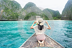 Asian female tourists ride on long-tailed Thai boats at Maya Bay, Krabi, Thailand