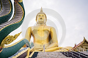 Asian female tourists stand in front Giant Golden Buddha statue at Wat Muang, Ang Thong Province, Thailand