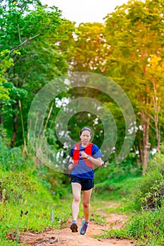 Asian female trail runners, wearing runners, sportswear, practice running on a dirt path in a forest. With a happy mood, there