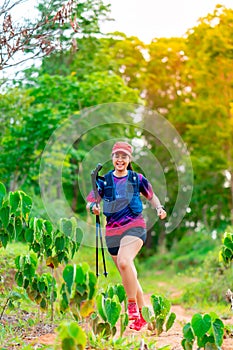 Asian female trail runners, wearing runners, sportswear, practice running on a dirt path in a forest. With a happy mood, there