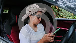 Asian female traveler uses a GPS navigation map on her smartphone while sitting in a car. Tourists travel in the forest on vacatio