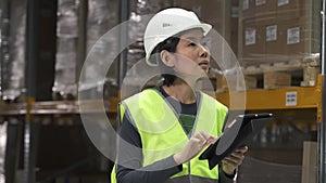 asian female warehouse worker with walkie talkie. racks with supplies. business, inspecting, cargo