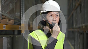 asian female warehouse worker with walkie talkie. shelves racks with supplies. concept logistics