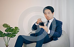 Asian Financial Advisor Drink Coffee and See Smartphone in Vintage Tone