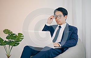 Asian Financial Advisor Touch Glasses and Use Laptop in Vintage Tone