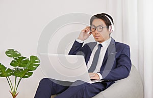 Asian Financial Advisor Touch Headphone and Use Laptop