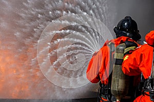 Asian firefighter on duty firefighting, Asian fireman spraying high pressure water, Fireman in fire fighting equipment uniform