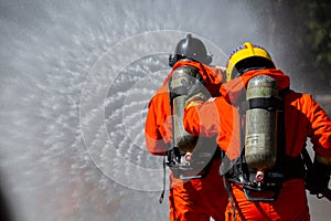 Asian firefighter on duty firefighting, Asian fireman spraying high pressure water, Fireman in fire fighting equipment uniform