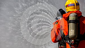 Asian firefighter on duty firefighting, Asian fireman spraying high pressure water, Fireman in fire fighting equipment uniform