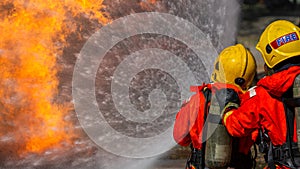 Asian firefighter on duty firefighting, Asian fireman spraying high pressure water, Fireman in fire fighting equipment uniform