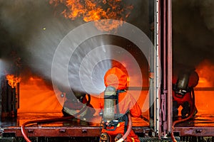 Asian firefighter on duty firefighting, Asian fireman spraying high pressure water, Fireman in fire fighting equipment uniform