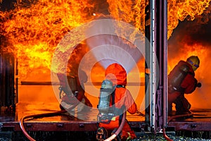 Asian firefighter on duty firefighting, Asian fireman spraying high pressure water, Fireman in fire fighting equipment uniform