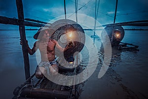 Asian fisherman holding a lantern on his boat waiting to fish in the Mekong
