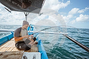 Asian fishermen pull in fishing rods during hook ups