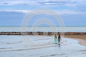 Asian fishermen walk along beach to catches fish with fishing net for the daily livelihood in the sea. Fishermen prepare their