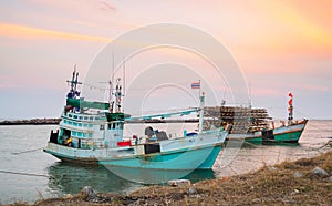 Asian fishing boats dock alongside the shore sunset ba