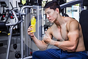 Asian fit man with energy drink relaxing and drinking in the gym. Sport and fittness concept.And Asian handsome muscles are tired