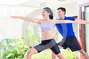 Asian fitness couple at sport workout in tropical home