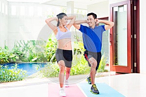Asian fitness couple at sport workout in tropical home