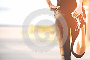 Asian fitness woman runner stretching legs before run outdoor workout in the park. photo