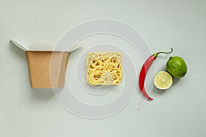 Asian food. Asian dried noodles with lime, chili and paper box, top view