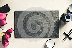 Asian food background - sake and chopsticks on a slate board over grey concrete background. Top view